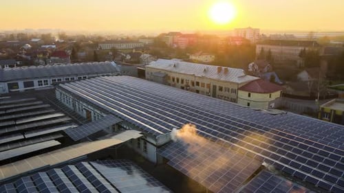 Aerial View of Solar Power Plant with Blue Photovoltaic Panels Mounted on Industrial Building Roof