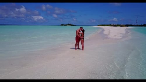 Young couple suntan on tranquil island beach holiday by blue sea with white sandy background of the