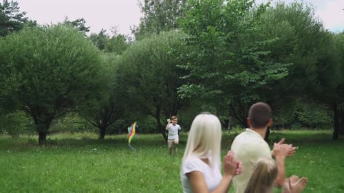 Family Day, Picnic in Nature, Boy Run Through a Clearing and Play with a Kite, Young Parents