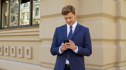 Smiling Businessman Using Phone Outside Office Building