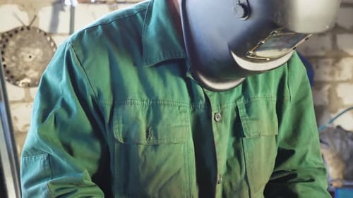 Repairman Holding Soldering Iron and Preparing to Weld Metal Parts at Garage