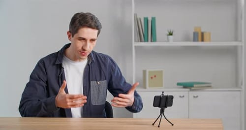Young Man Talks to Smartphone Camera on Tripod