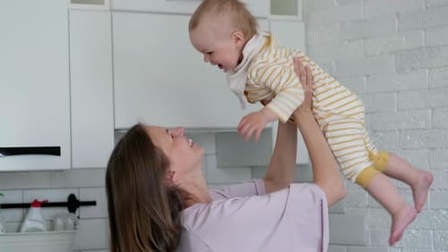 Mother Lifts Baby in Sunny Kitchen, Affectionate Moment