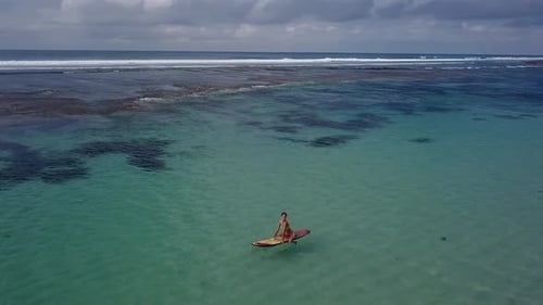 Woman Relaxing in the Sea on a Surfboard