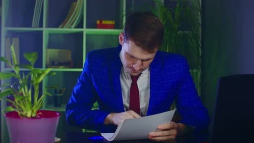 Serious Businessman Checks Papers and Puts Signature Sitting in Office