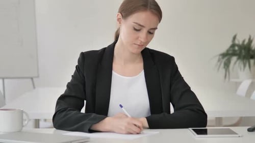 Woman Writing at Desk in Bright Office
