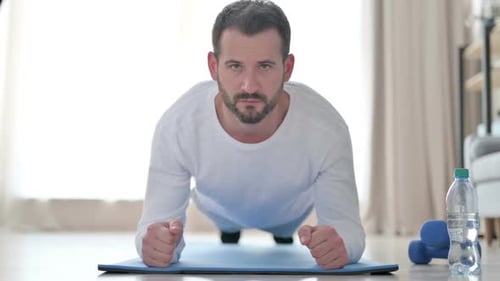 Nahaufnahme eines starken Mannes, der zu Hause Planke auf Yogamatte macht