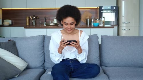 Woman using smartphone on couch in her apartment