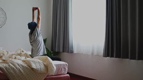 Person Stretches on Bed in Bright Bedroom