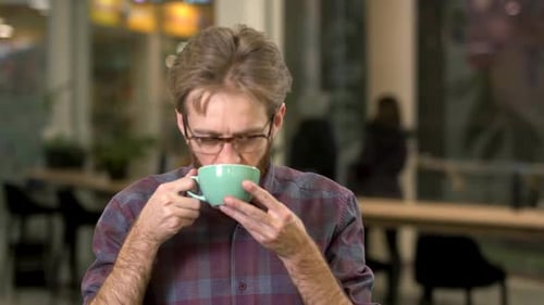 Young Adult Drinks Coffee in Modern Workplace