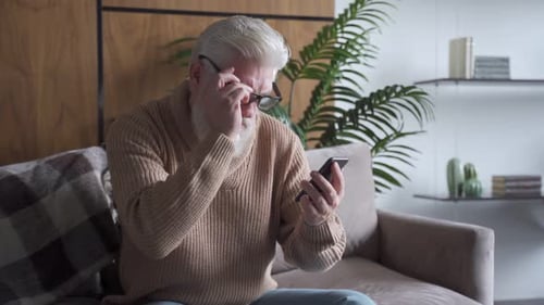 Senior Man Using Smartphone with Glasses in Home