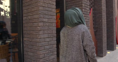 Rückansicht einer muslimischen Frau, die auf die Straße geht