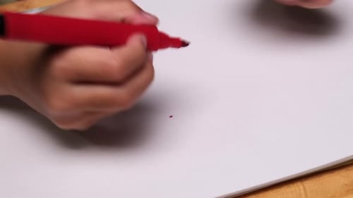 Close-up of a little girl drawing a heart and coloring with her colored markers