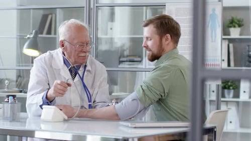 Doctor Checks Young Adult Patient's Blood Pressure in Office