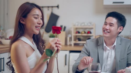 Man Presents Rose to Woman at Romantic Dinner