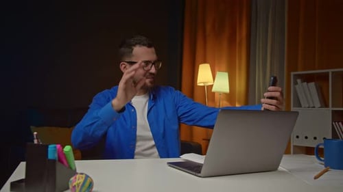 Man Video Calling on Mobile Phone at Desk