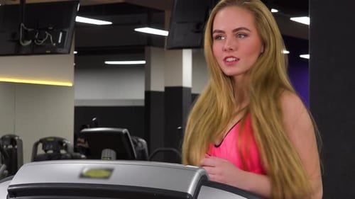 A Young Beautiful Woman Runs on a Treadmill in a Gym - Closeup