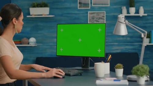 Woman Working on Personal Computer with Mock Up Green Screen Chroma Key Display
