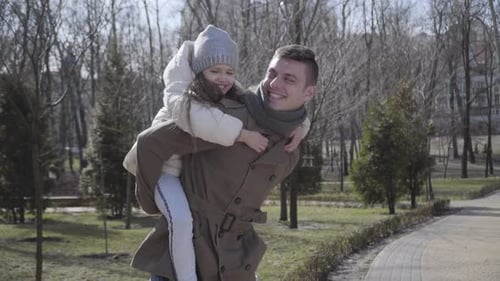 Man Gives Piggyback Ride to Child in Park