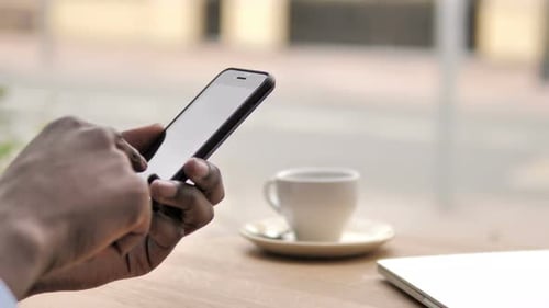 African Hands Using Smartphone in Outdoor Cafe