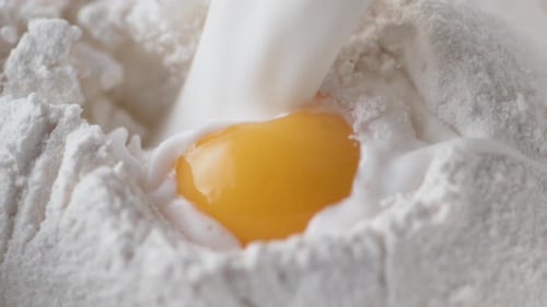 Milk Pouring Over Egg Yolk and Flour