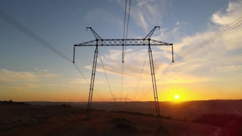 Dark Silhouette of High Voltage Tower with Electric Power Lines at Sunrise