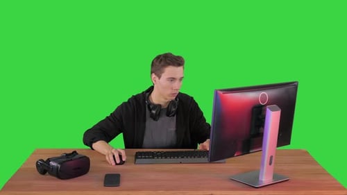 Gamer Playing a Video Game on Personal Computer on a Green Screen, Chroma Key.