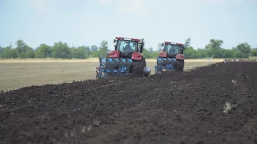 Tractors Plowing Field on Sunny Day