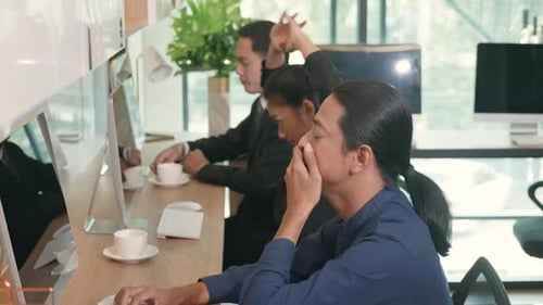 Tired businessteam yawning during working on computer sitting at desk office