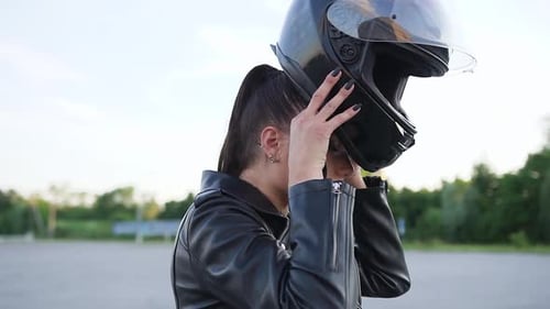 Stylish Woman Puts on Motorcycle Helmet Outdoors
