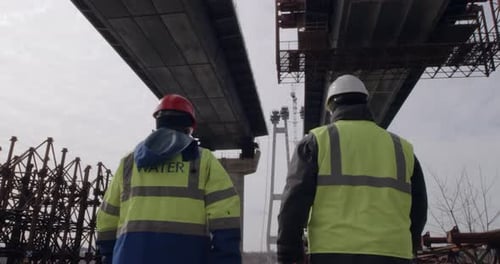 Des hommes méconnaissables inspectent le chantier de construction d'un pont