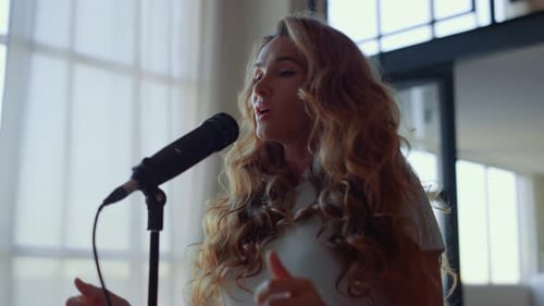 Young Woman Practicing Vocal in Room. Female Vocalist Singing in Microphone
