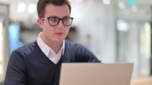Young Man Video Calling on Laptop in Office