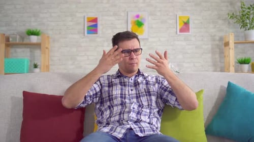 Man Expressing Frustration on Couch in Living Room