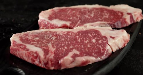 Raw Beef Striploin Steak on a Cutting Board Rotates.