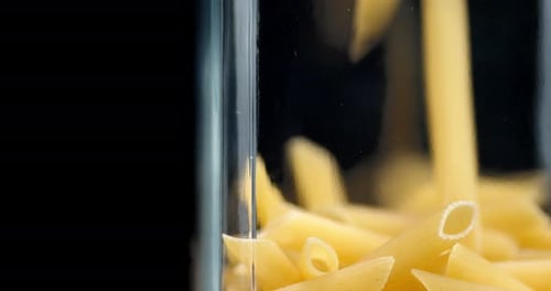 Penne Pasta Pouring into a Glass Jar