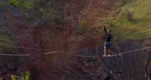Athlete Balancing on Highline Tightrope Between Rock Cliffs