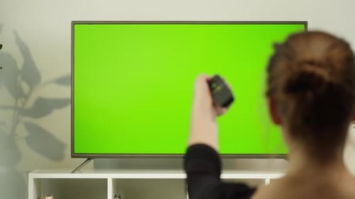 Woman Watching TV with Green Screen in Living Room Back View