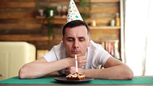 Sad Man With Birthday Cake Blows Out Candle