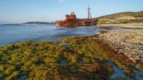 Rusted Shipwreck on a Rocky Beach by Blue Ocean