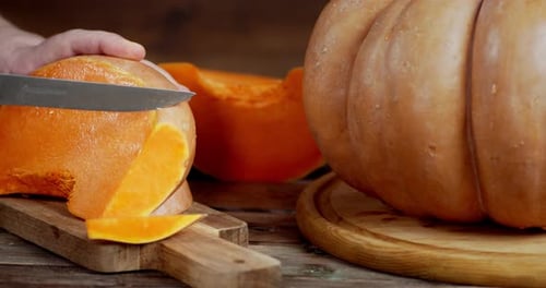 Men's Hands Cut the Pumpkin Into Pieces.