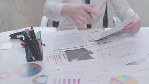 Businessman works with charts in the office at the table and signs documents
