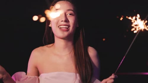 Smiling Woman Holding Sparklers at Night