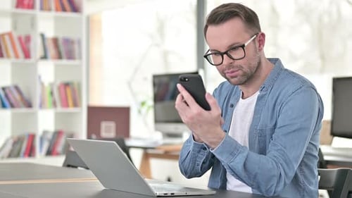 Man Using Laptop and Smartphone in Home Office