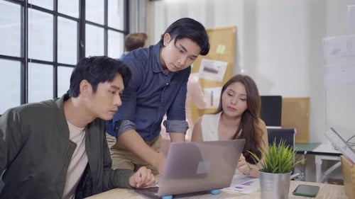 Young Adults Collaborating on Laptop in Modern Office