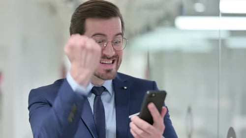 Excited Businessman Celebrates Success with Smartphone
