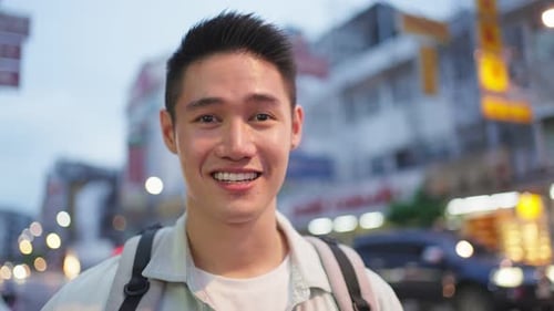 Asian attractive man backpacker walking around the city at night road.