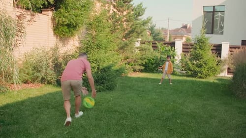 Father and Son Play Frisbee in Backyard