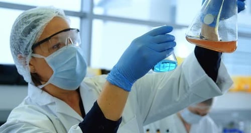 Woman Lab Worker Pouring Liquids in Beaker