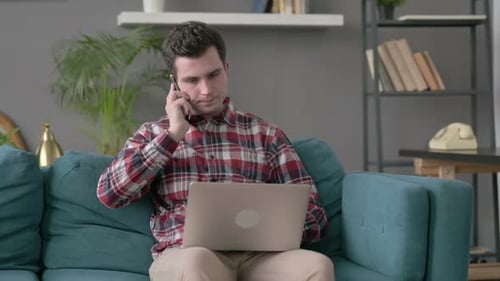 Young Adult Using Laptop and Talking on Phone